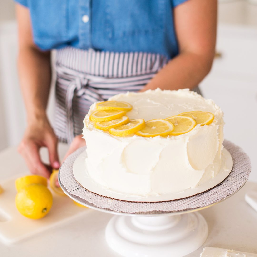Cake by Courtney - Chocolate Lemon Zucchini Cake #chocolatecake #chocolatezucchinicake #lemoncreamcheesefrosting #chocolatelemonzucchinicake Chocolate Zucchini Cake on a turntable with lemons.
