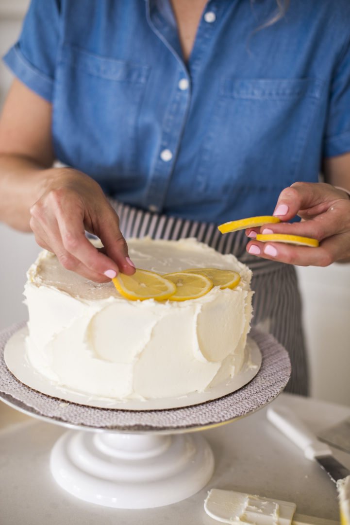 Cake by Courtney - Chocolate Lemon Zucchini Cake #chocolatecake #chocolatezucchinicake #lemoncreamcheesefrosting #chocolatelemonzucchinicake Woman adding lemon to the top of a cake.
