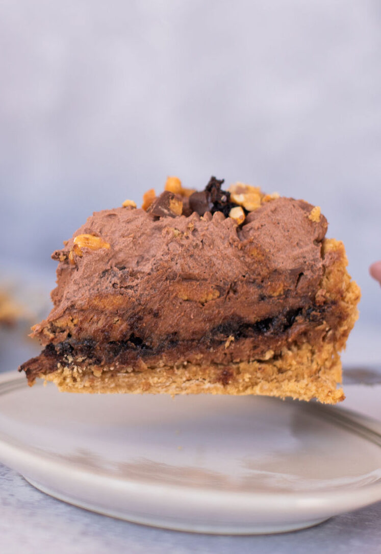 A slice of peanut butter brookie pie being put on a plate.