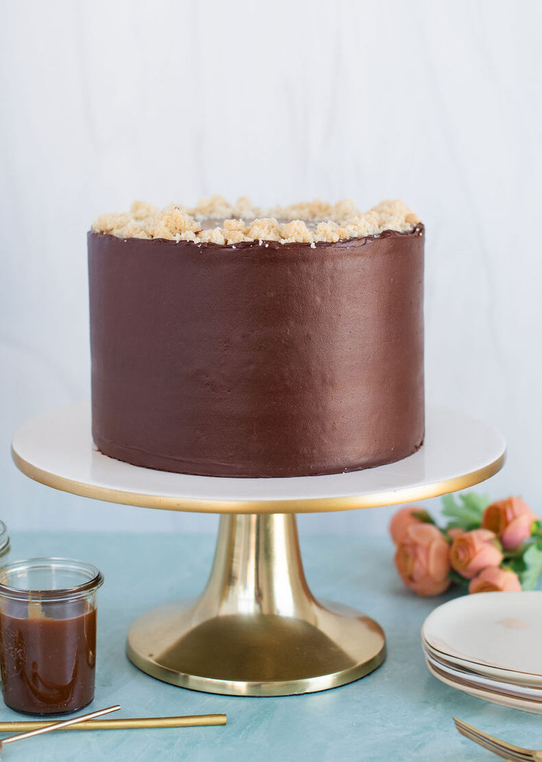 A chocolate cake on a gold cake stand.