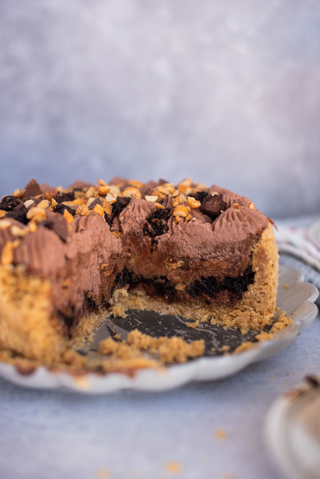 A peanut butter brookie pie on a plate with a section cut out of it so you can see the inside.