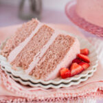 A slice of strawberry cake on a plate with pink napkins.