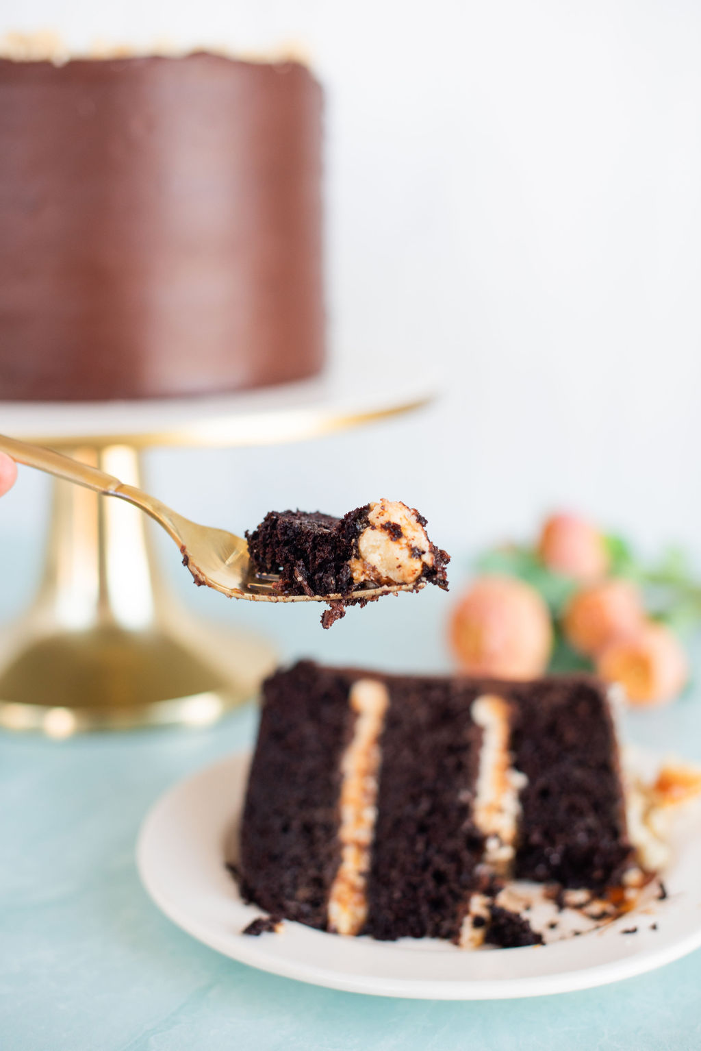 A slice of cake on a plate, with the full cake behind it and a bite of the cake on a fork.