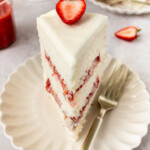 A slice of strawberry rhubarb cake on a plate with a fork.
